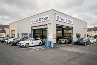 Vue d'ensemble d'un garage carrossier professionnel dans le Val-d'Oise avec des véhicules en attente de réparation